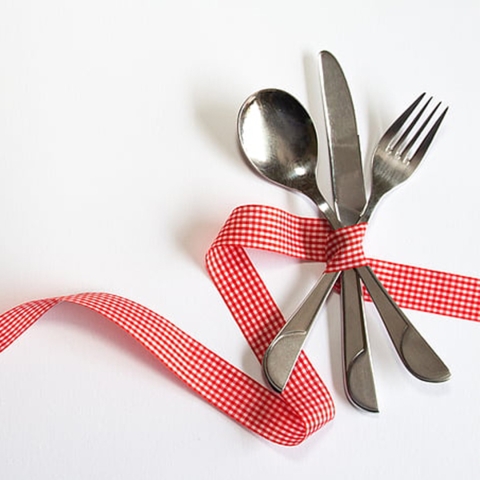 spoon, knife, and fork wrapped in a red ribbon