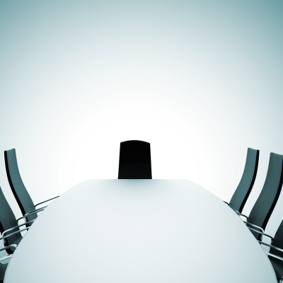 Long table surrounded by empty office chairs