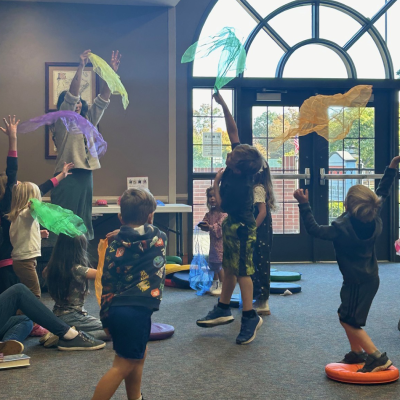 Children in a story hour program tossing scarves in the air