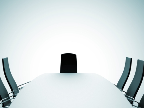 Long table surrounded by empty office chairs