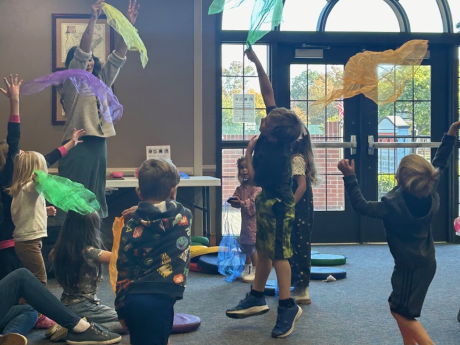 Children in a story hour program tossing scarves in the air