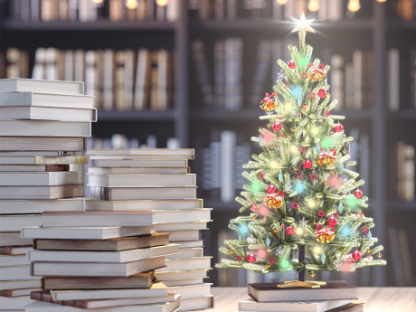 Small Christmas tree on a table with books stacked next to it