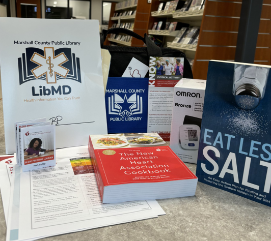 A display of materials from the LibMD kit for high blood pressure. Included are the books Eat Less Salt and The American Heart Association Cookbook; a blood pressure cuff; printed materials; a blood pressure log; and a brochure on exercise.