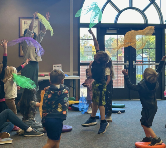 Children in a story hour program tossing scarves in the air