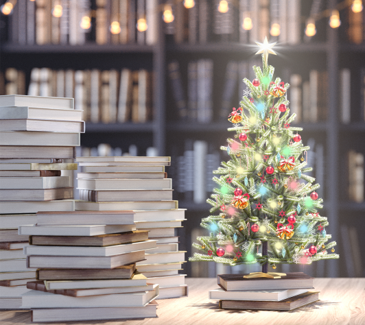 Small Christmas tree on a table with books stacked next to it