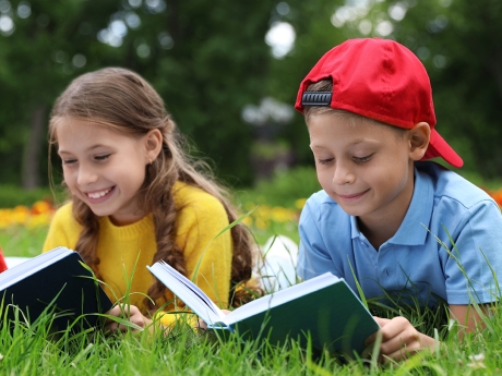 A young boy and girl reading in the grass