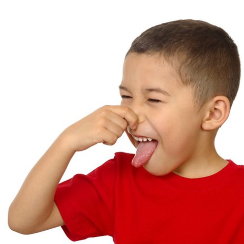 a little boy in a red shirt holding his nose and sticking out his tongue as if he smells something bad