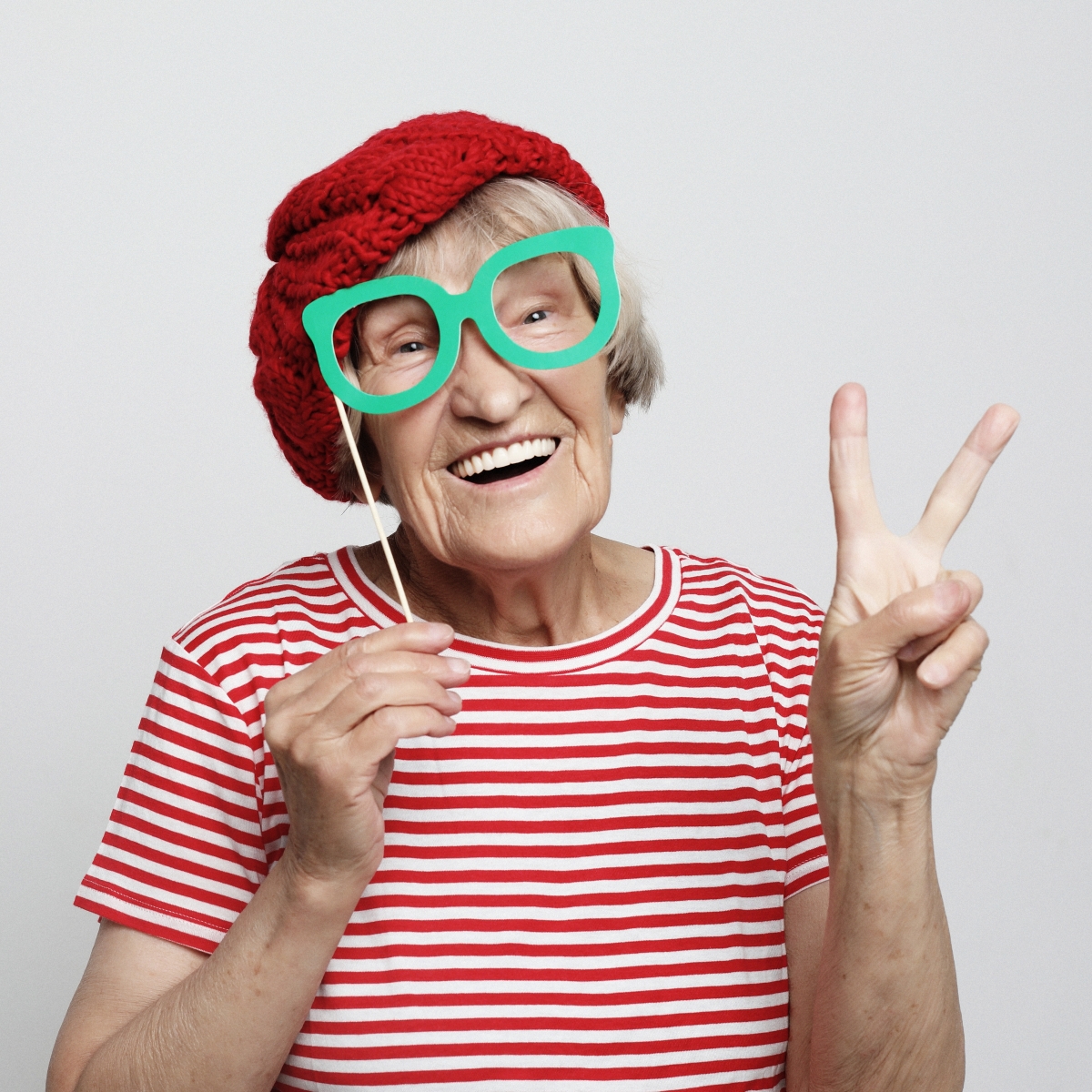 An retired woman with prop glasses giving the peace sign