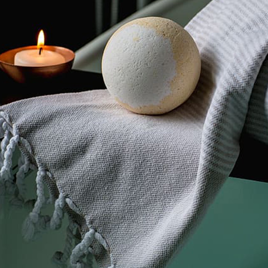 bath bomb sitting on a throw with a candle in the background