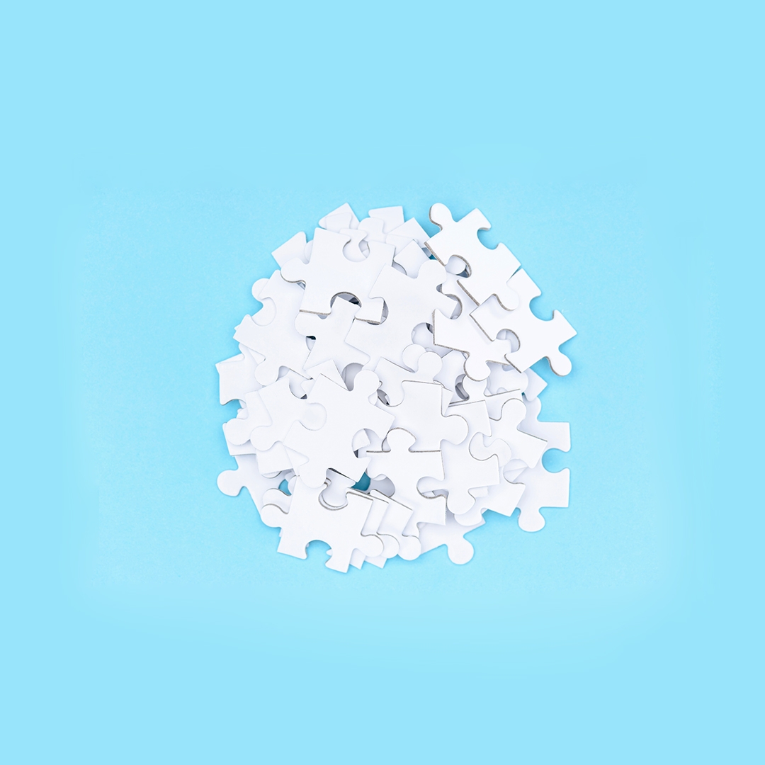 white puzzle pieces in a pile on a blue background