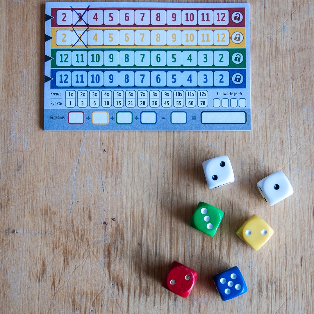 a multi-colored Qwixx score sheet and multi-colored dice